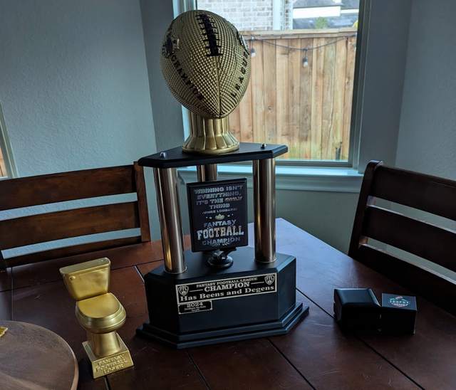 Has Beens and Degens league championship trophy beside the golden toilet loser trophy
